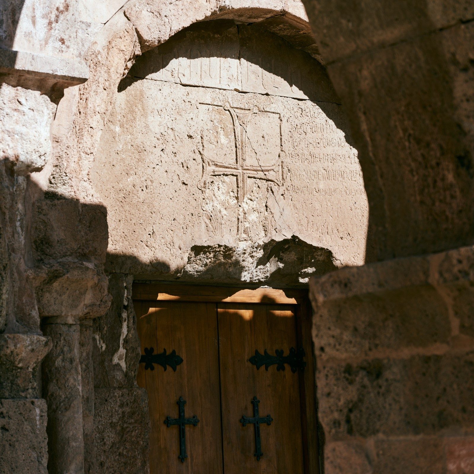 Carved cross stone above a wooden door, Armenia