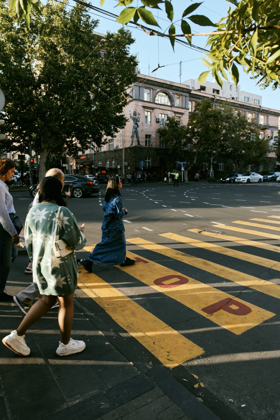 People crossing a yellow-striped street in the autumn sun, Yerevan, Armenia