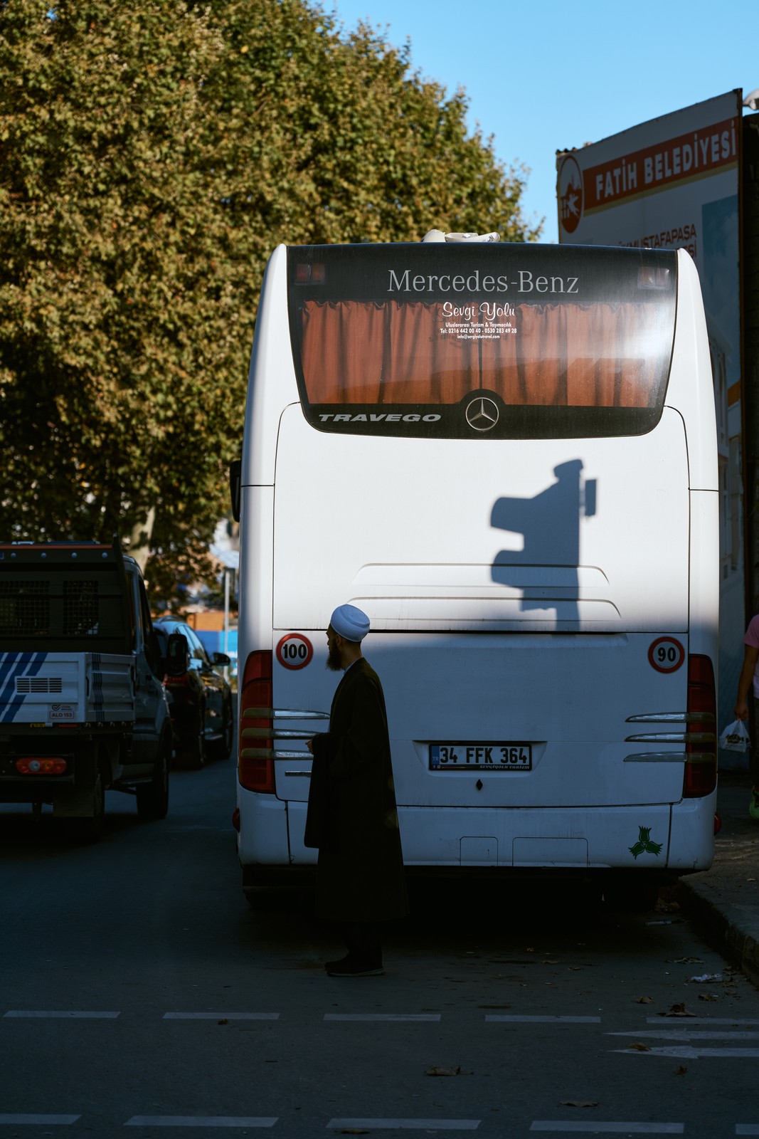Bearded imam waiting beside a tour bus on a street in Istanbul