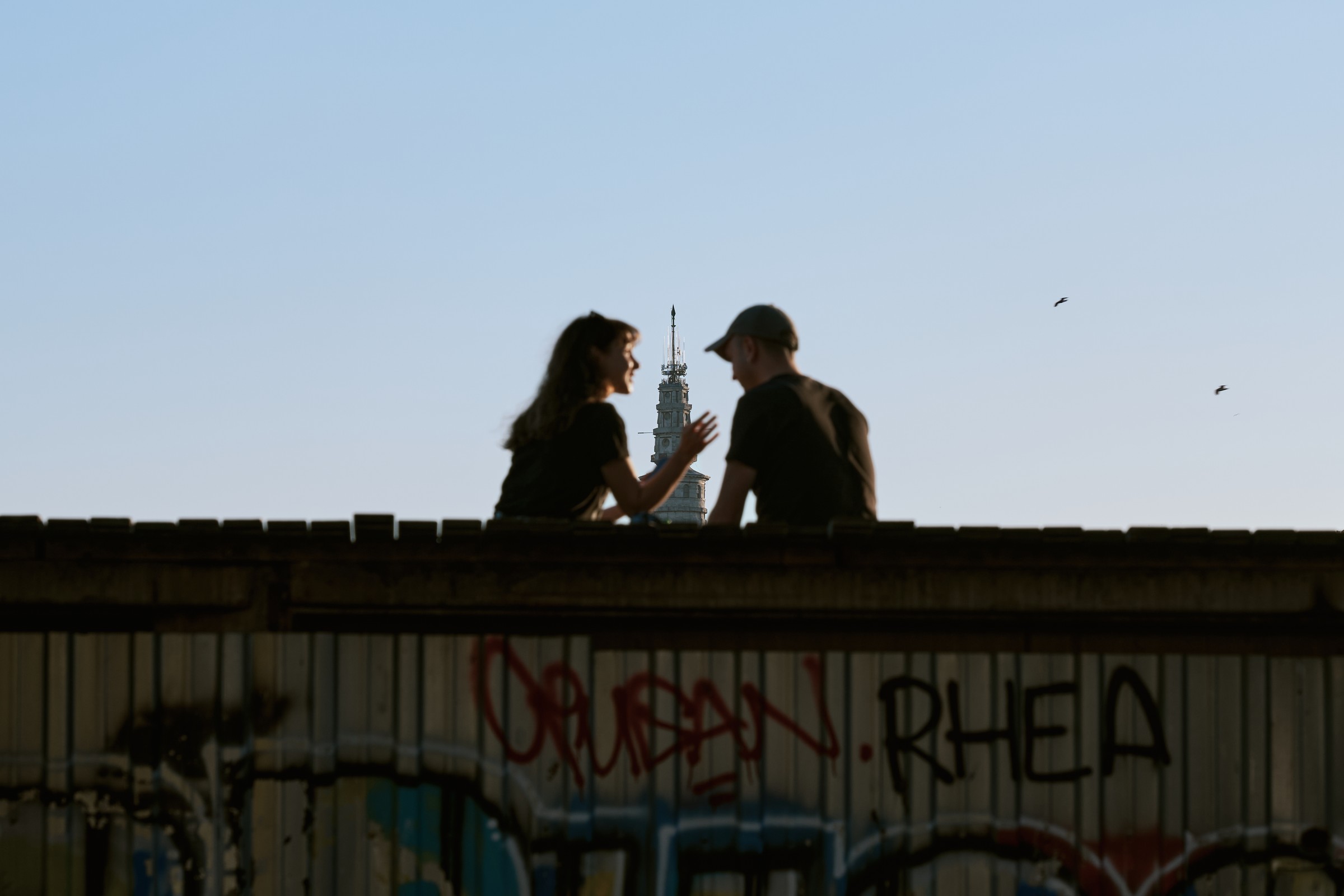 Young people silhouetted on a rooftop with a clock tower behind, Istanbul