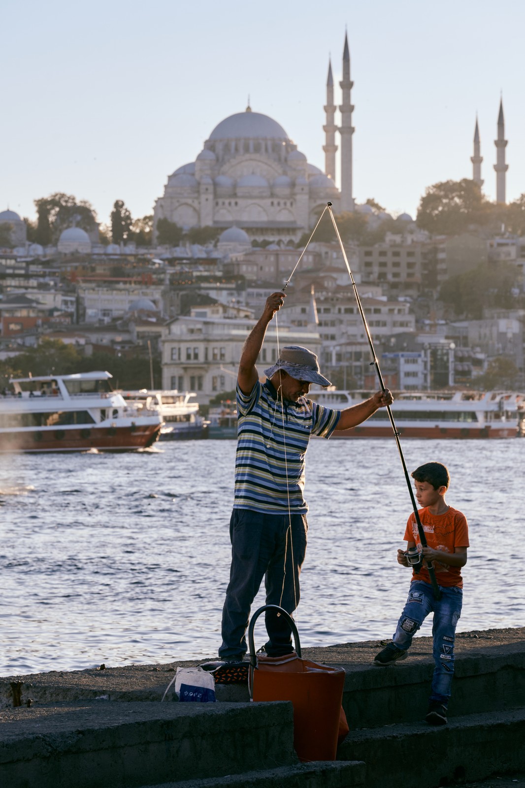 Father and son fishing on the Golden Horn with the Suleymaniye Mosque behind, Istanbul
