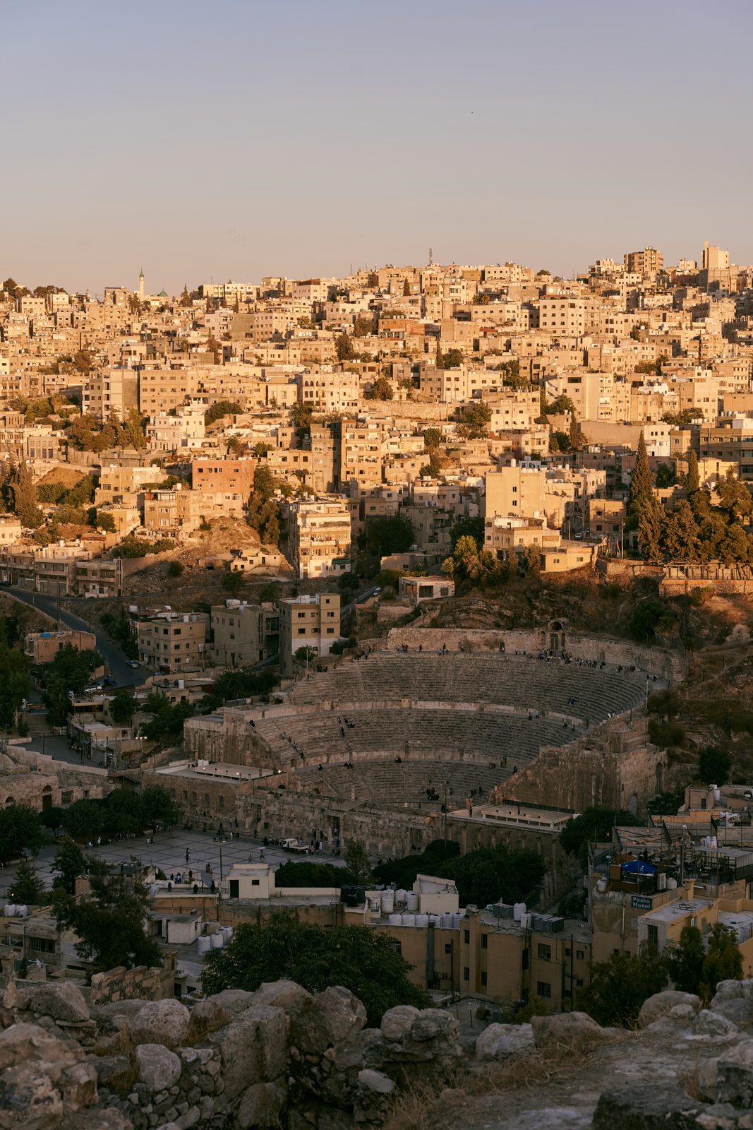Ancient theatre among hillside houses in low sun