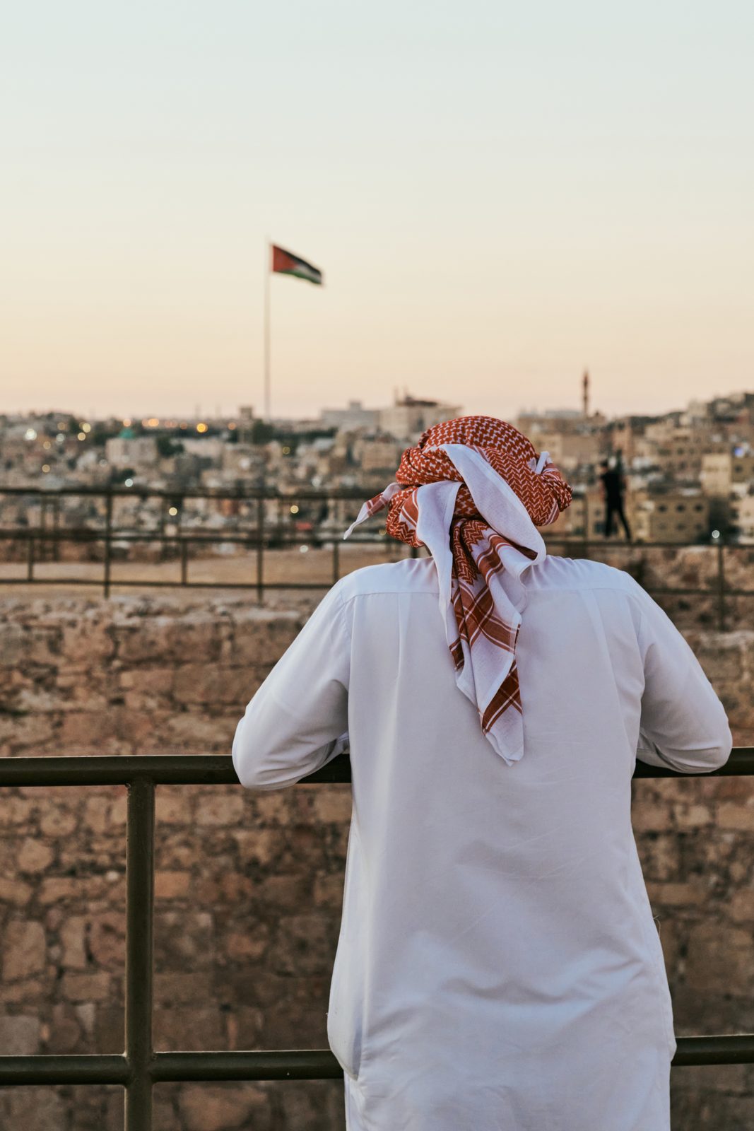 Man in a red and white keffiyeh looking over the city
