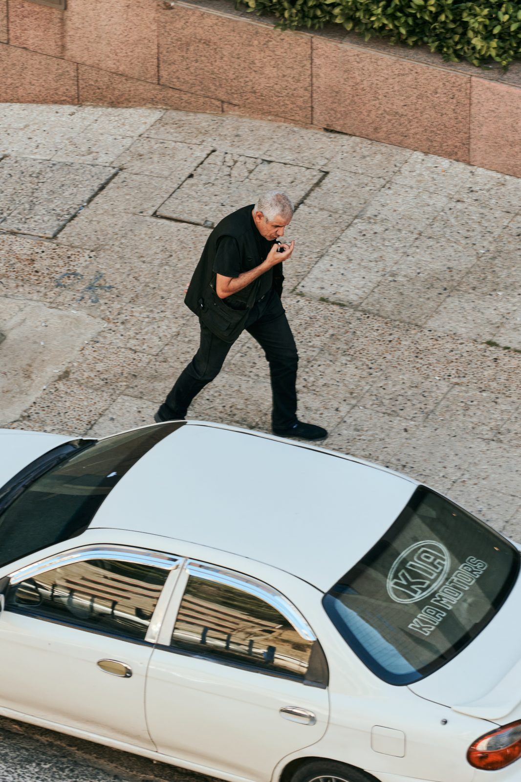 Overhead view of a man walking past a white car