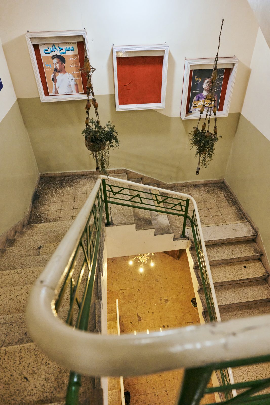 Looking down a stairwell with a green railing and framed pictures
