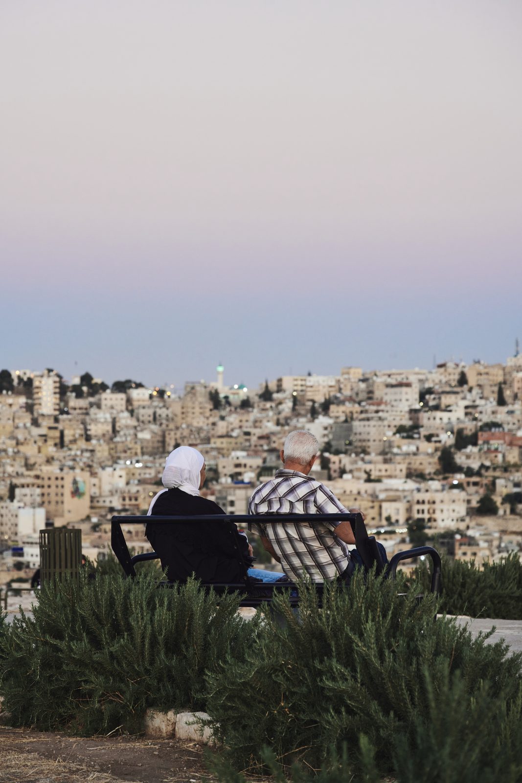 Older couple on a bench looking over the city at dusk