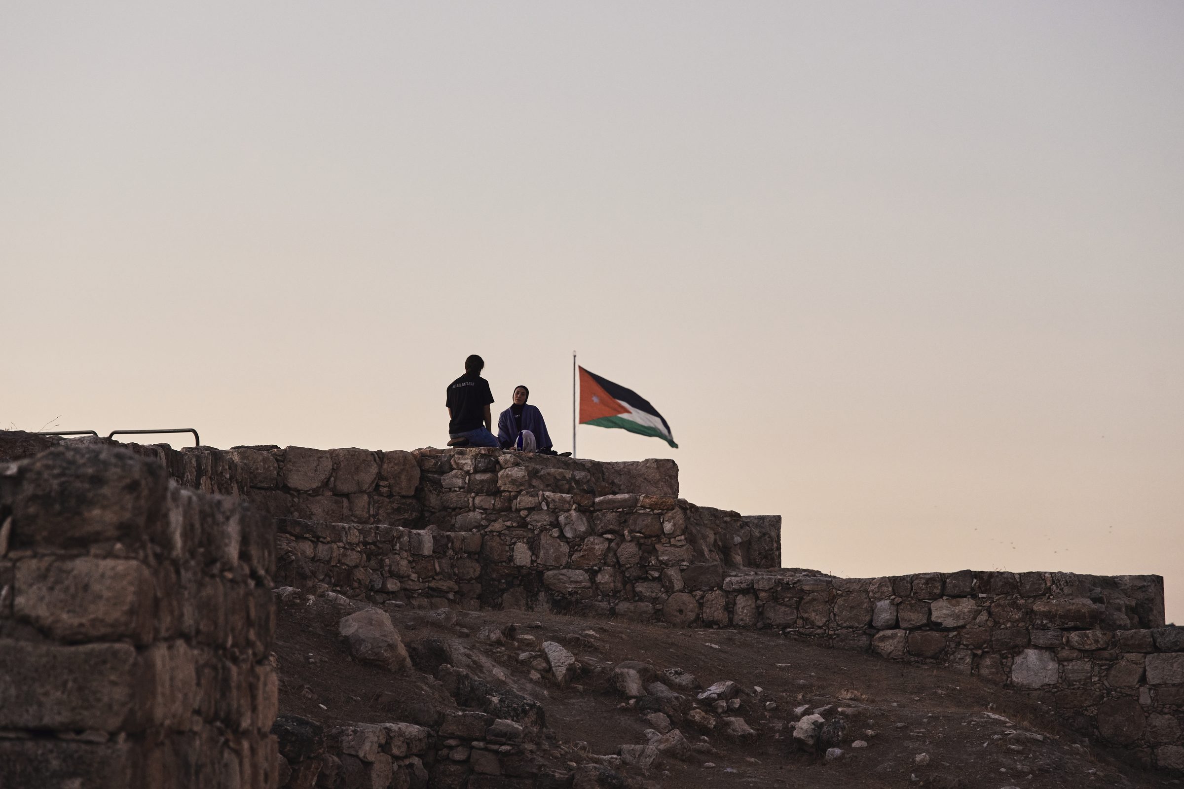 Two silhouettes and a flag on an old stone wall