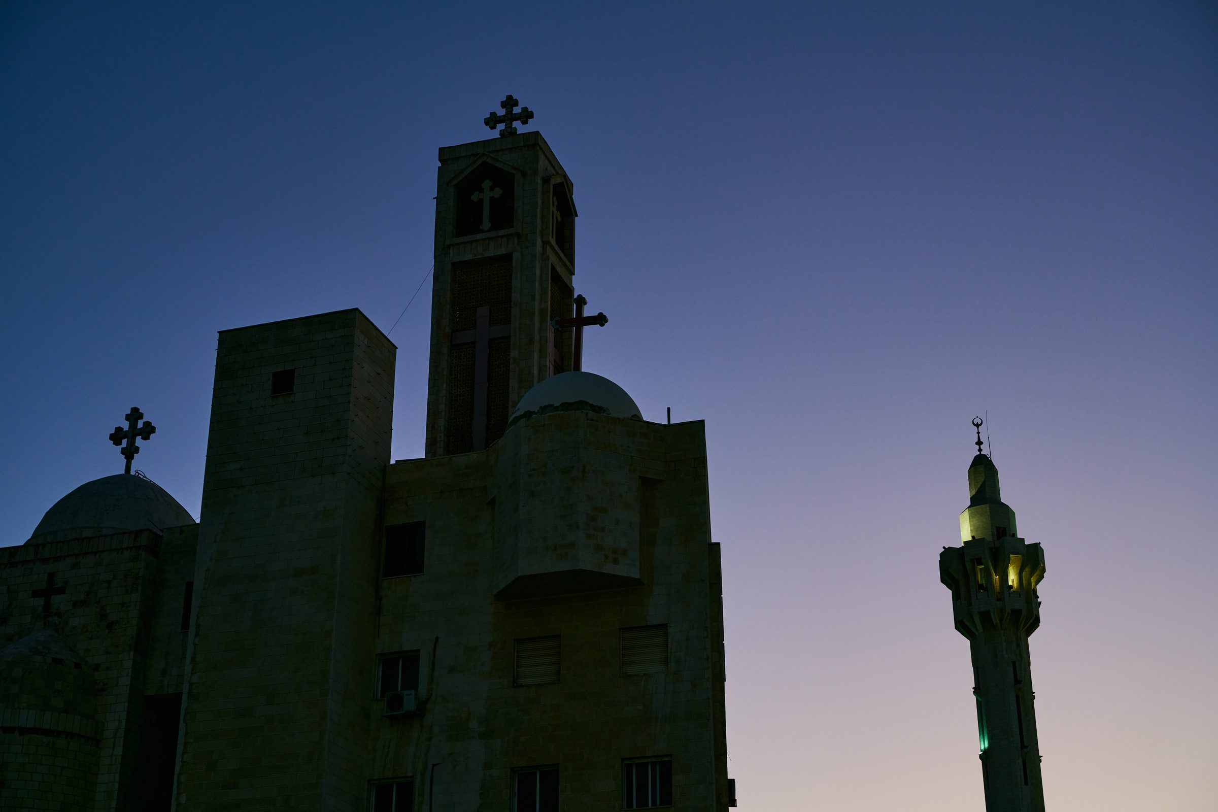 Silhouettes of a church and a minaret at dusk