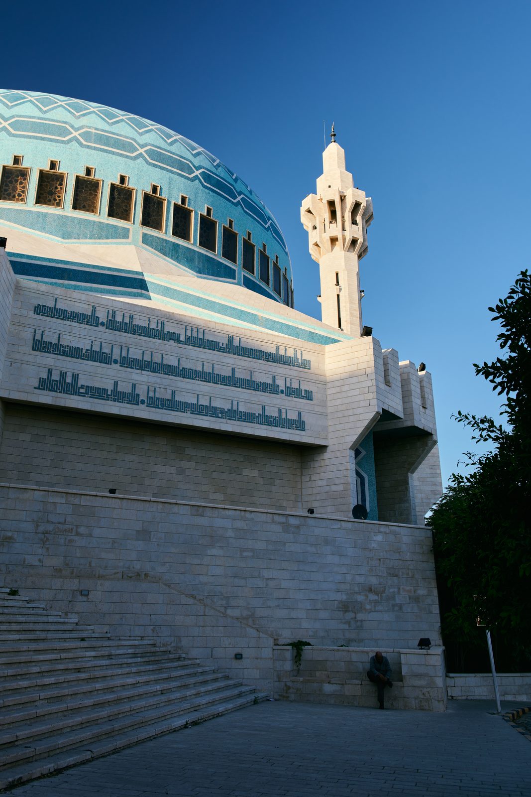 Blue-tiled mosque dome and minaret against deep blue sky