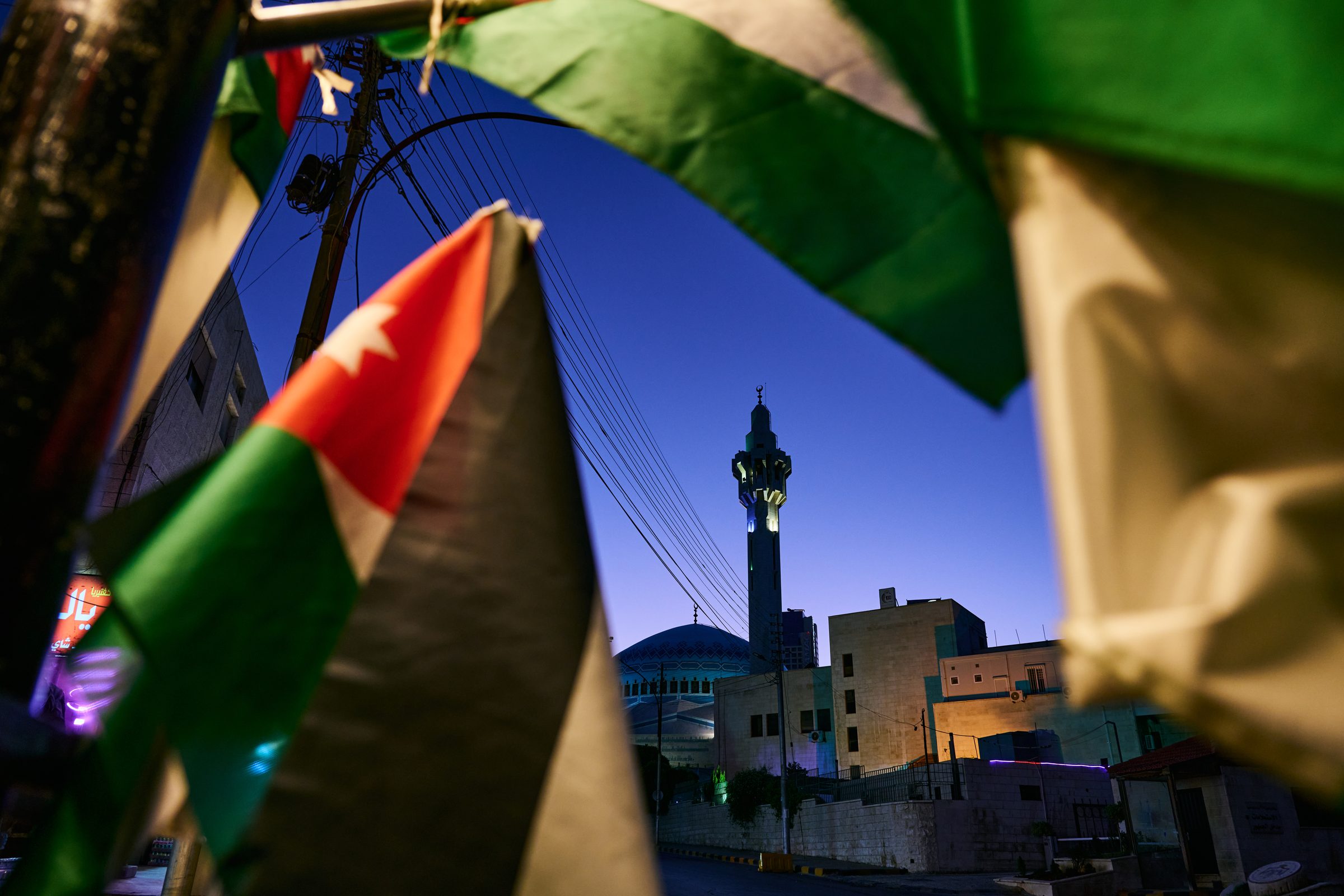 Flags close up with a minaret and blue dome behind at blue hour
