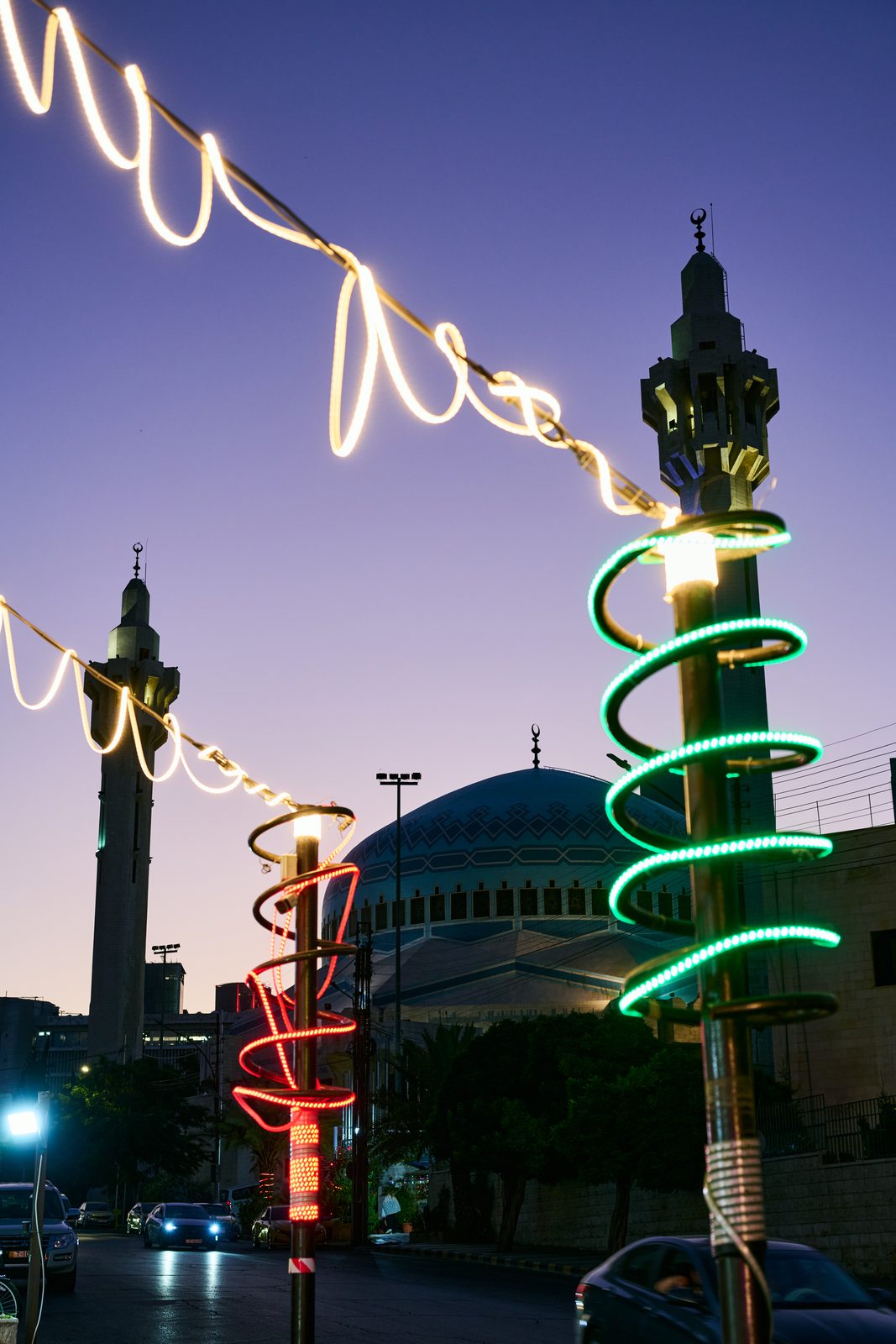 Neon spirals and string lights before minarets and a blue dome