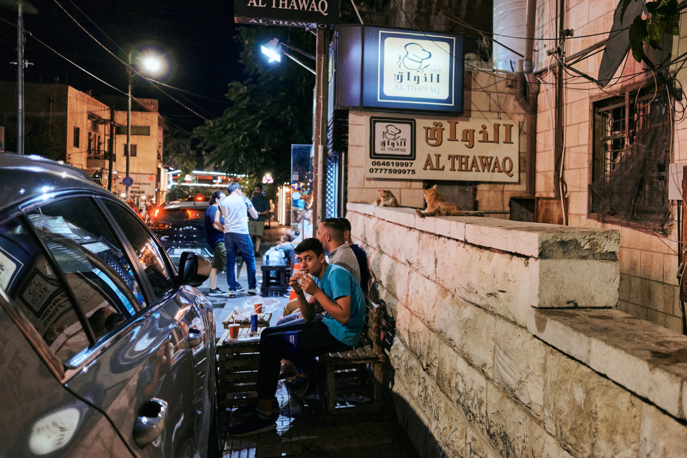Men at a street-side table outside a café at night