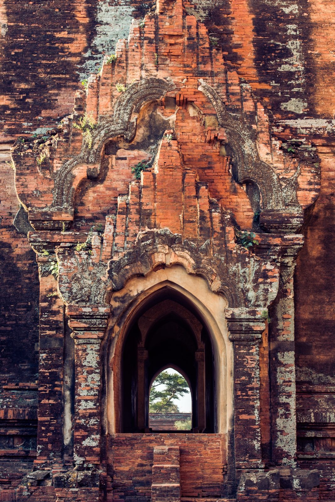 Brick archway detail with trees seen through the window opening, Bagan, Myanmar