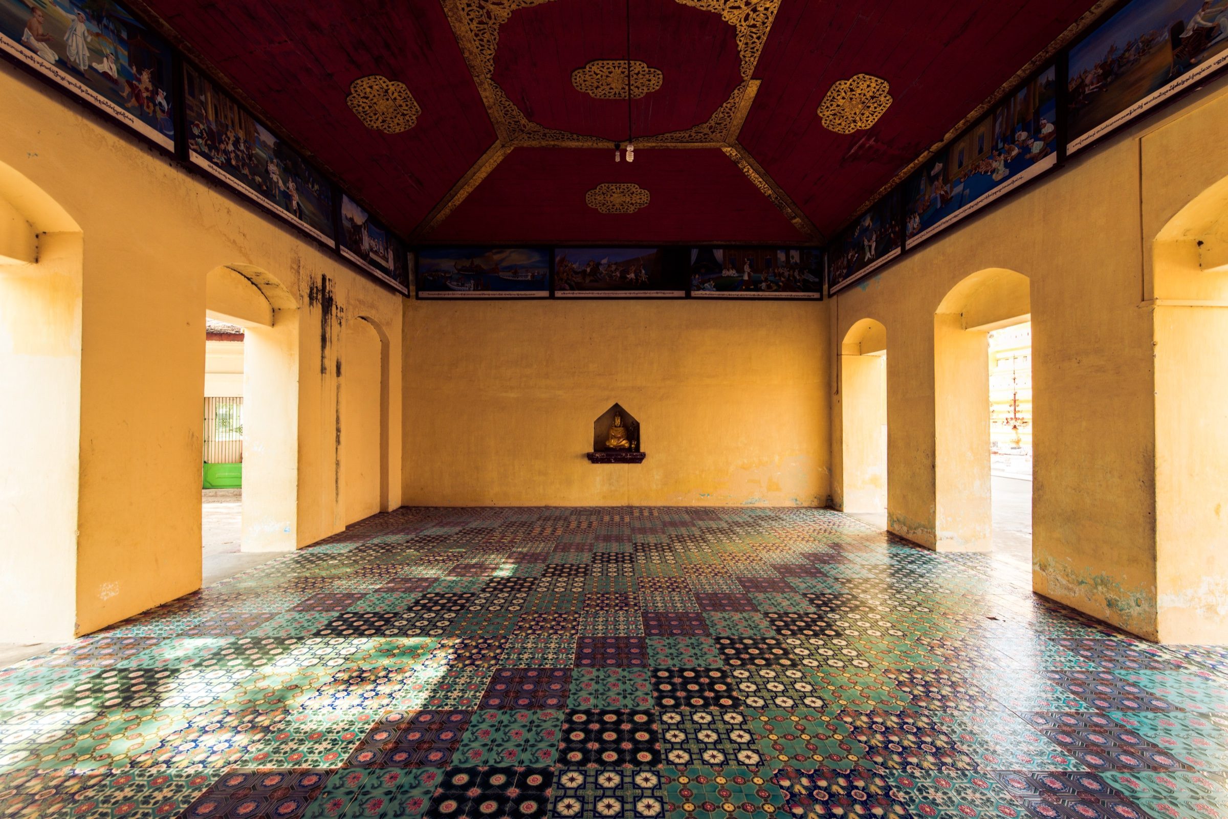 Colorful tiled floor and Buddha niche with patches of sunlight, Myanmar