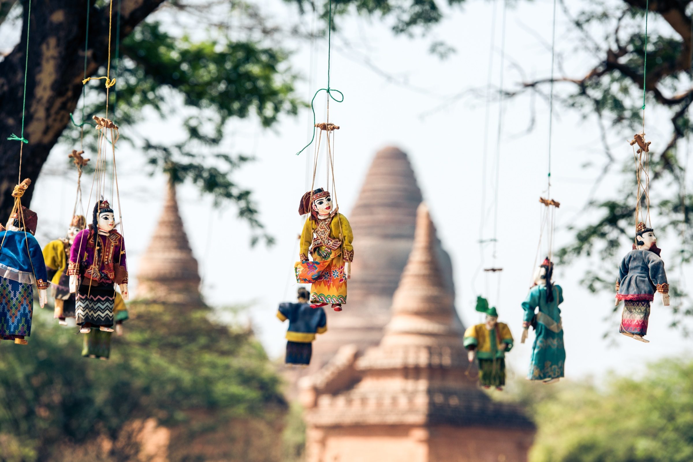 Traditional marionette puppets hanging with Bagan's pagodas in the background, Myanmar