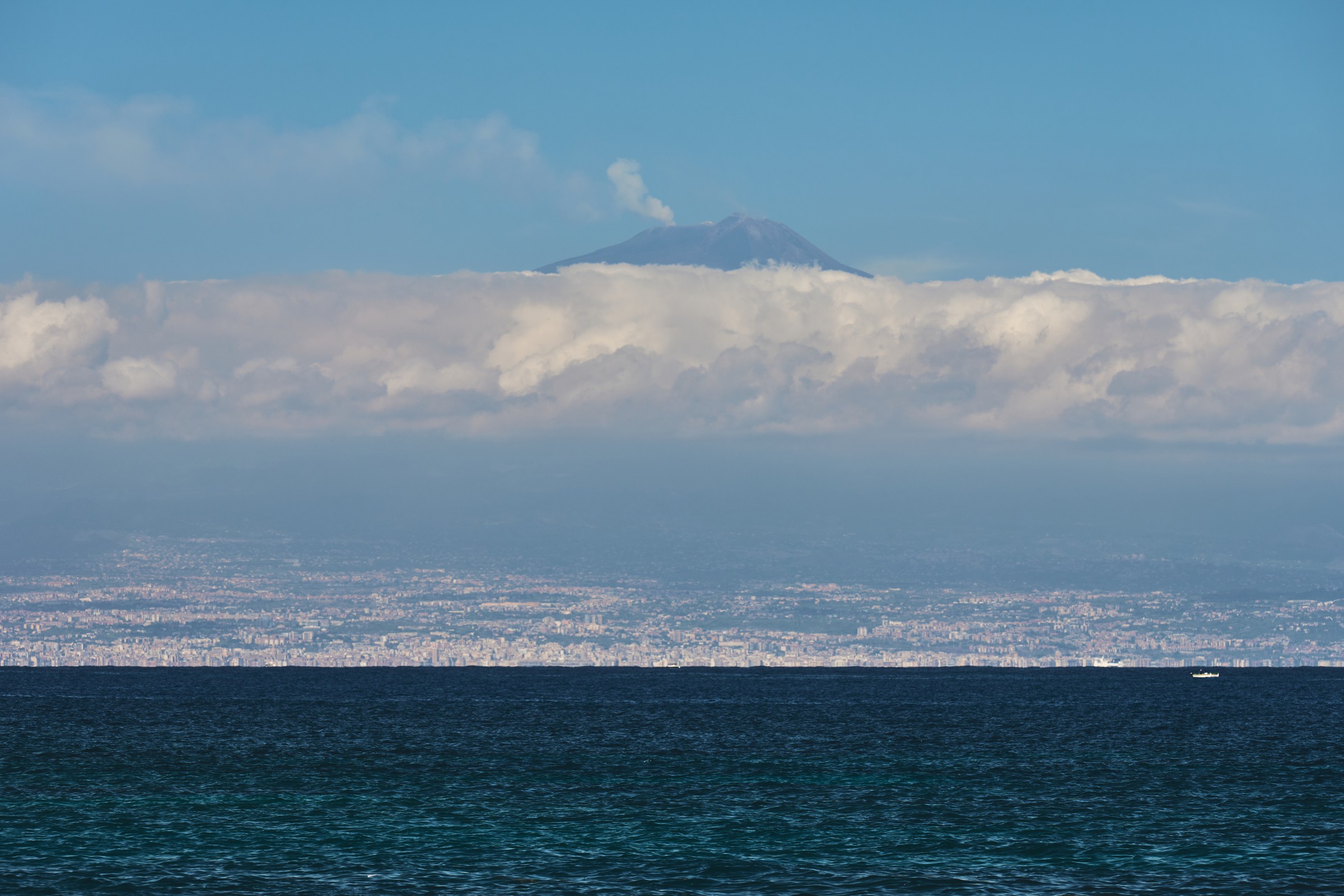 云层之上冒烟的埃特纳火山，海面远眺