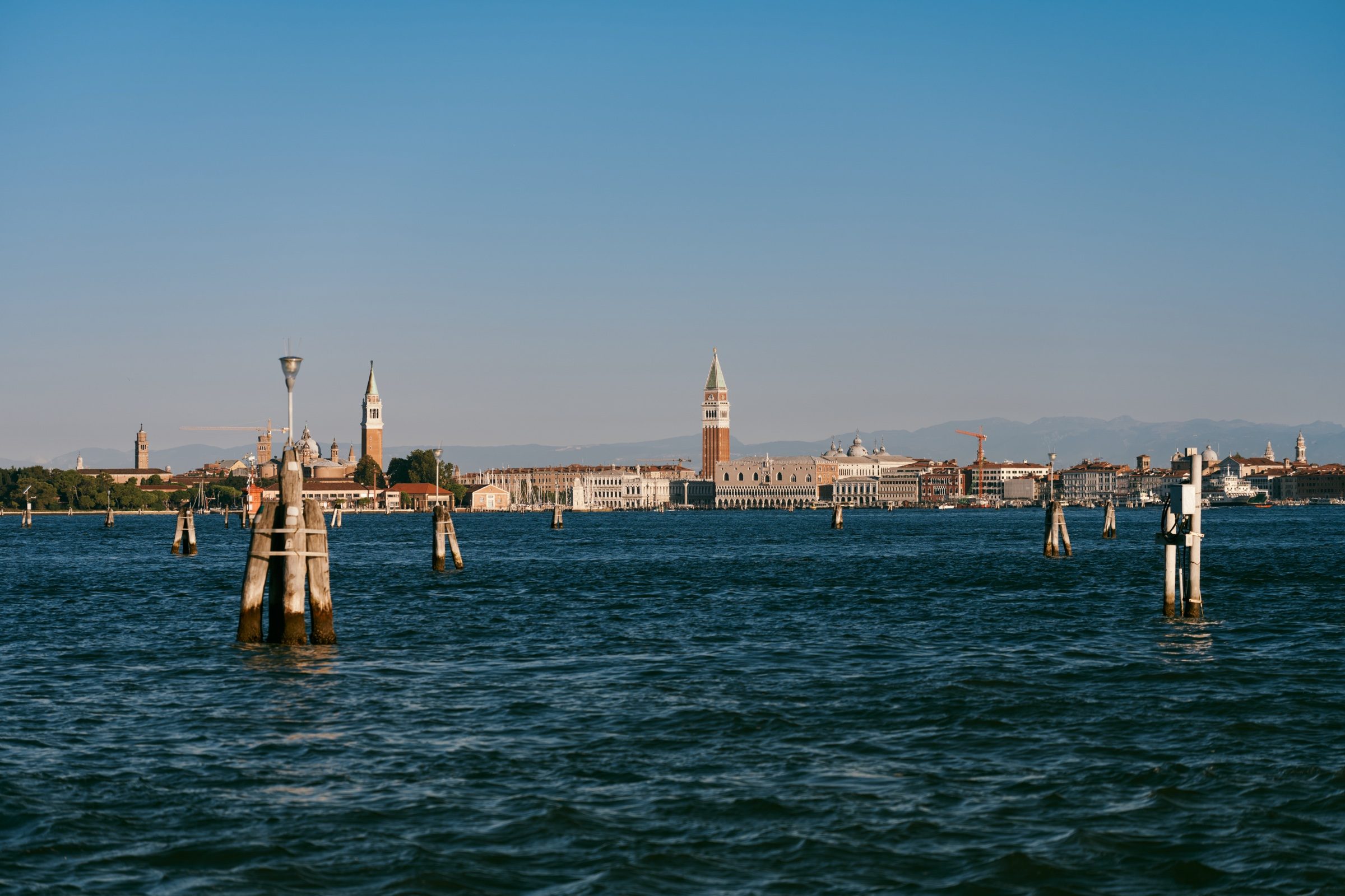 Mooring posts in the lagoon with the Venice skyline and campanile on the horizon