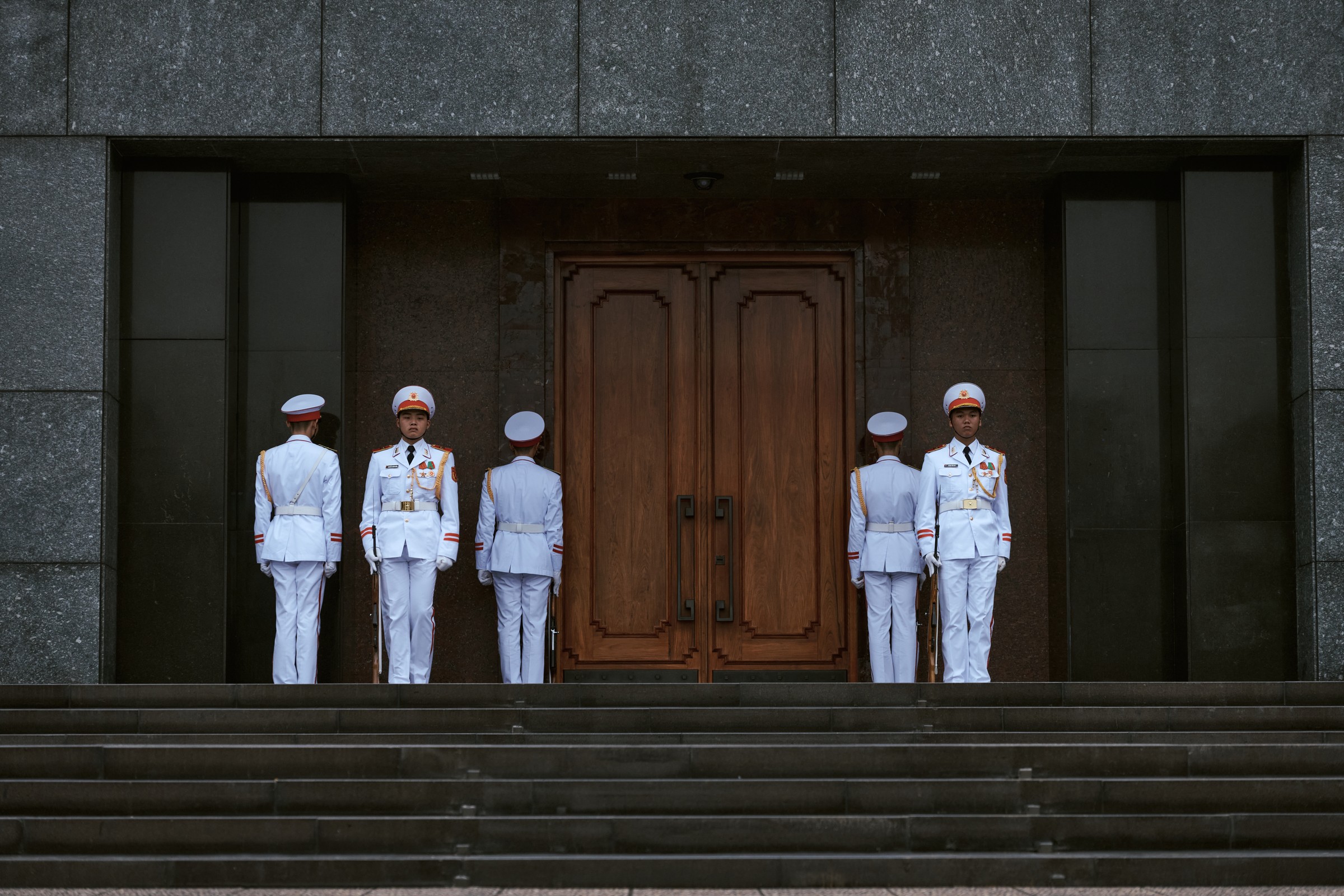 Honor guards in white uniforms before the doors of the Ho Chi Minh Mausoleum, Hanoi, Vietnam