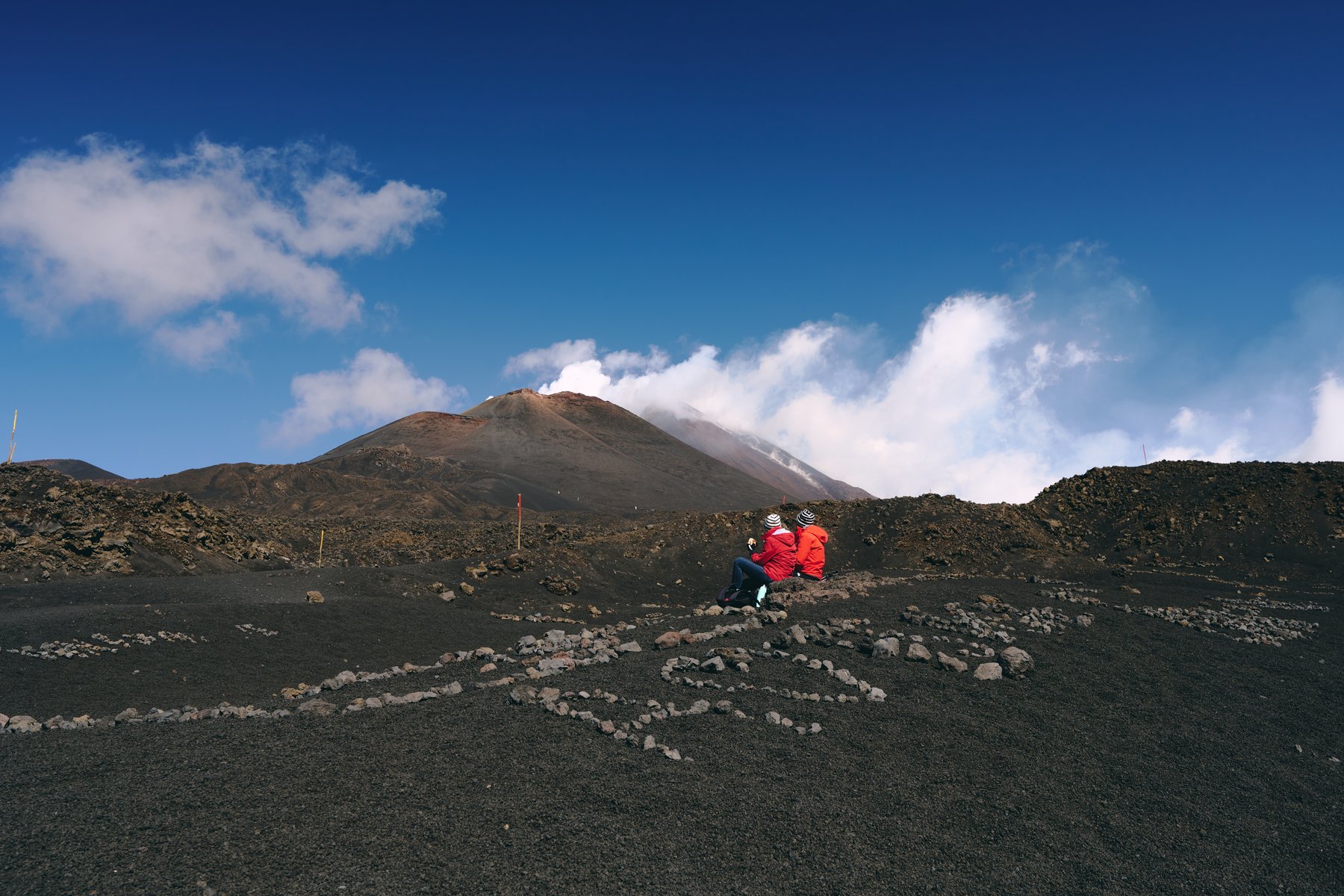 两人坐在火山岩石堆上眺望