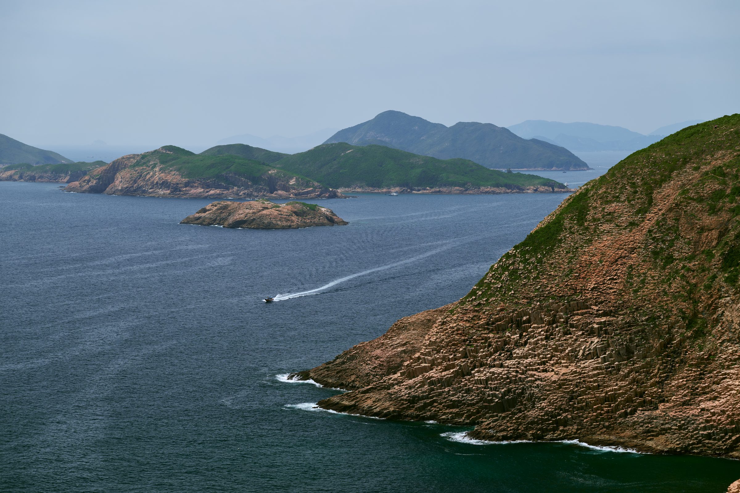 Small island and distant headlands with a boat wake on the sea, seen from the MacLehose Trail, Sai Kung, Hong Kong