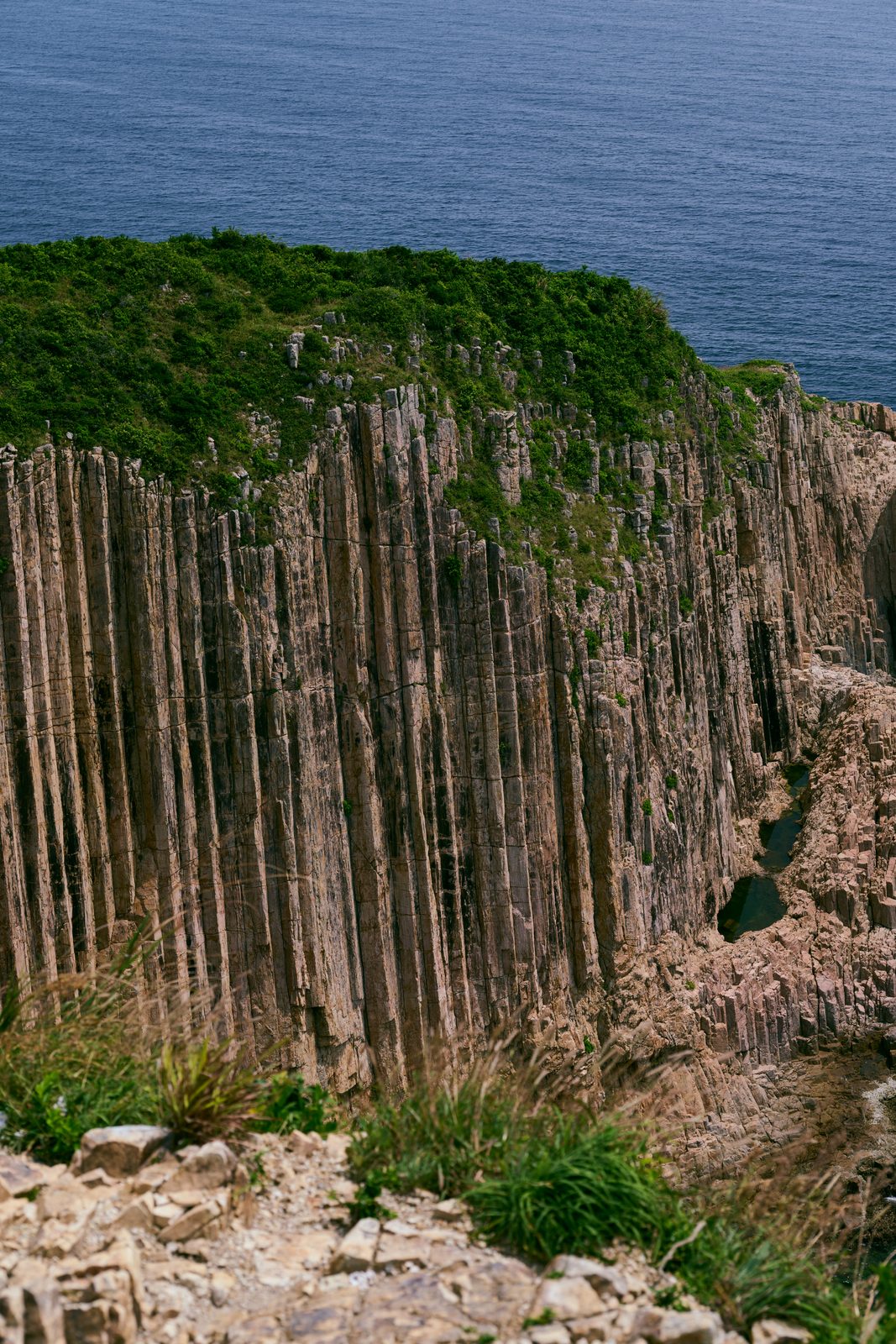 Tall hexagonal rock columns topped with vegetation, MacLehose Trail, Sai Kung, Hong Kong