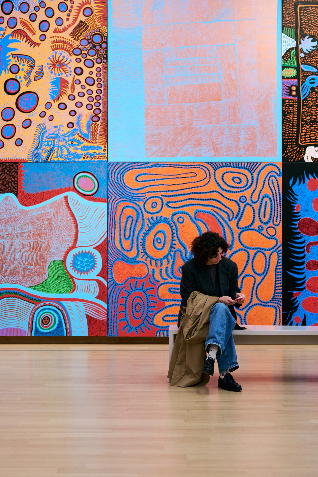 Visitor seated before a wall of large colorful Kusama paintings, Stedelijk Museum Amsterdam