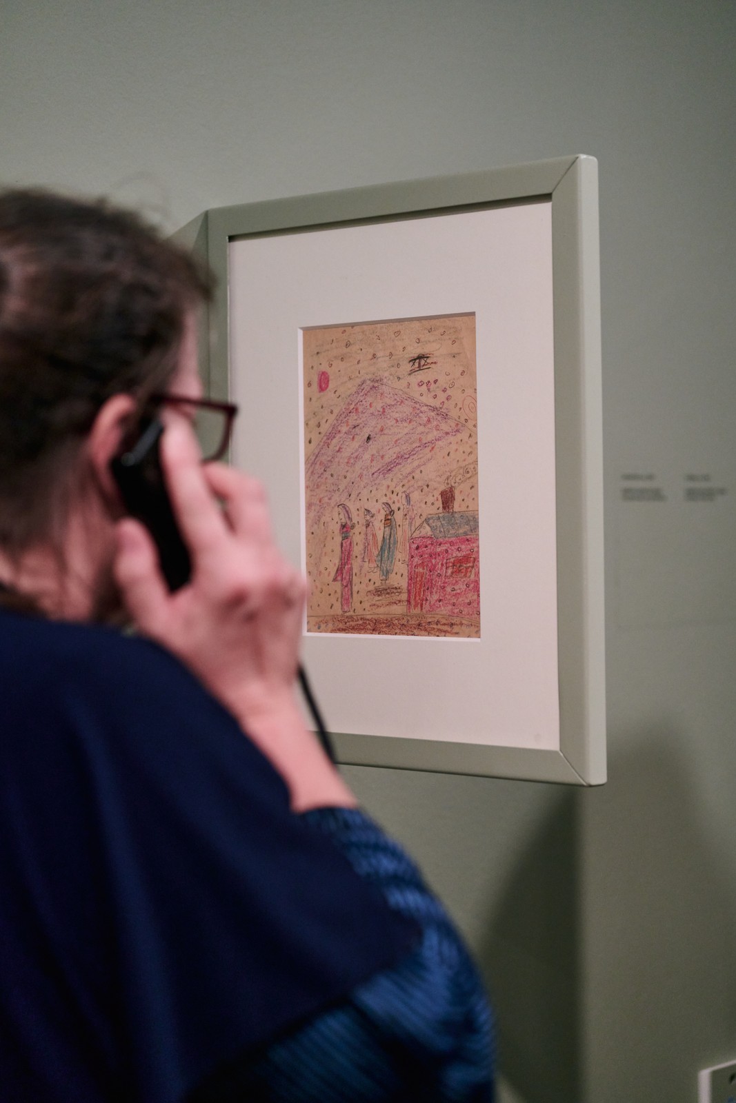 Visitor on the phone before an early pastel drawing with figures by Yayoi Kusama, Stedelijk Museum Amsterdam