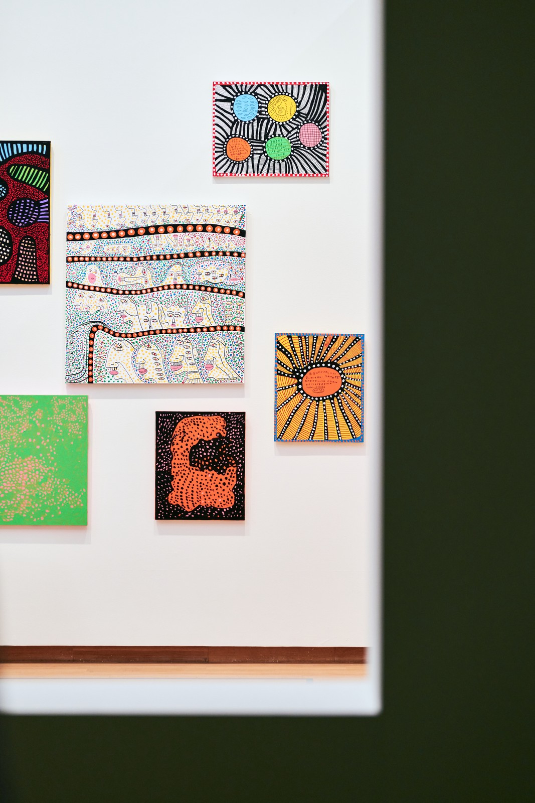 Salon-style wall of small Kusama paintings seen through a window opening, Stedelijk Museum Amsterdam