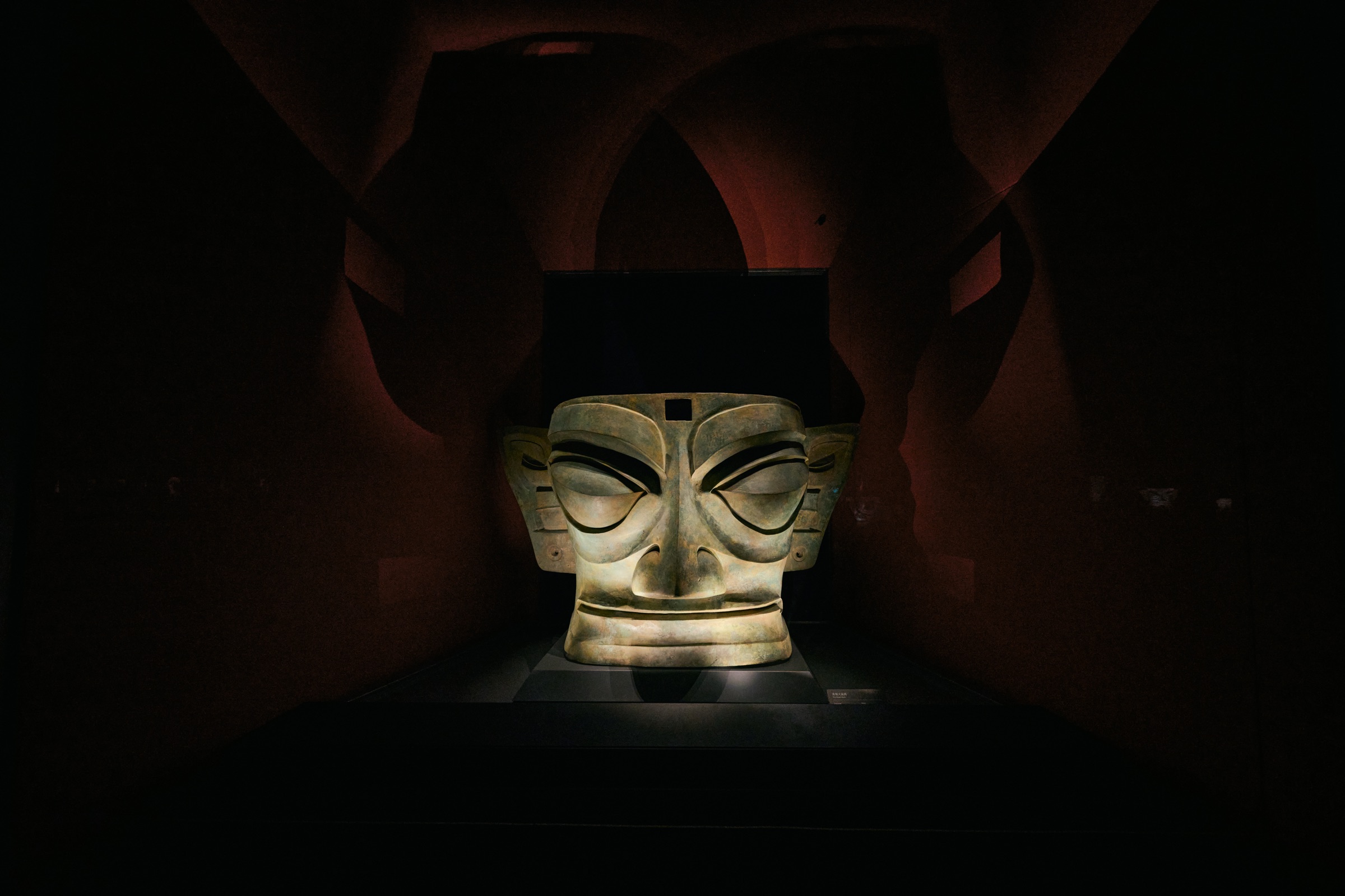 Large bronze mask under dark-red arched drapery, Sanxingdui Museum, Guanghan, China